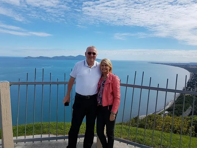 Ein Paar posiert an einem Aussichtspunkt mit Blick auf Küste und Meer.